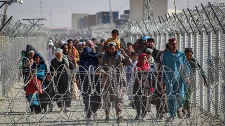Afghanen gehen an Zäunen entlang, als sie am 24. August 2021 nach der militärischen Übernahme Afghanistans durch die Taliban über den pakistanisch-afghanischen Grenzübergang in Chaman in Pakistan ankommen.