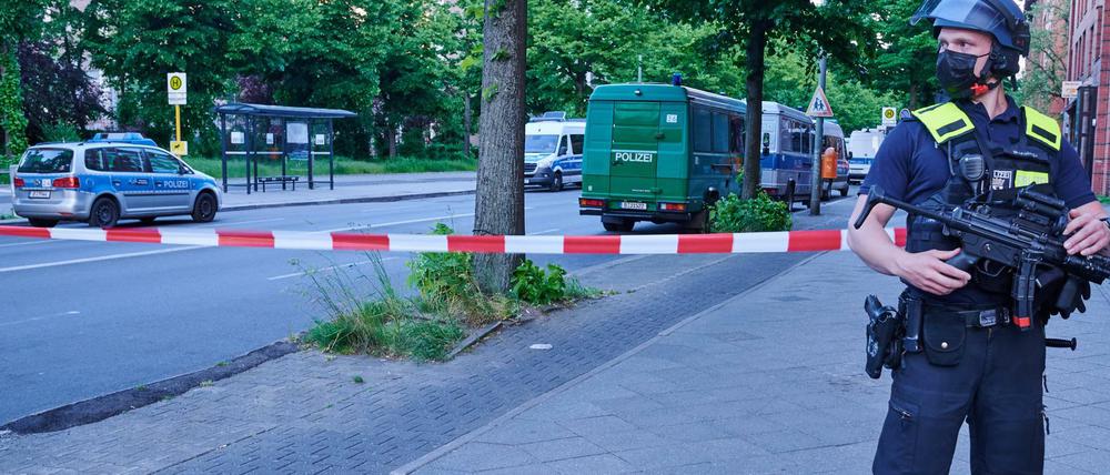 Ein schwer bewaffneter Polizist steht vor einer Absperrung in der Oranienstraße. Polizeiwagen stehen vor der Senatsverwaltung für Gesundheit. In dem Gebäude soll ein unbekannter Angreifer einen Bundeswehrsoldaten angegriffen haben.
