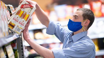 Ein Supermarkt-Mitarbeiter trägt beim Einräumen von Ware einen Mundschutz.