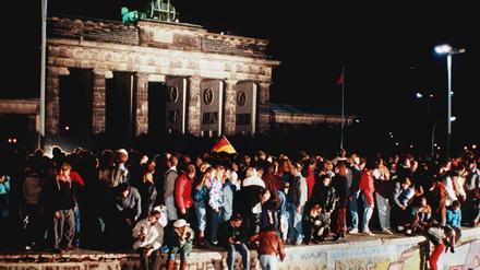 Jubelnde Menschen stehen am 9. November 1989 auf der Mauer vor dem Brandenburger Tor. 