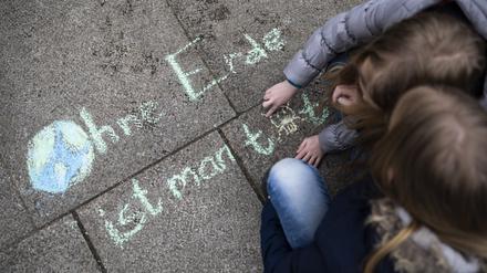 Zwei Mädchen schreiben bei der Klima-Kundgebung "Fridays for Future" am Invalidenpark den Satz "Ohne Erde ist man tot" mit Kreide auf den Boden. 