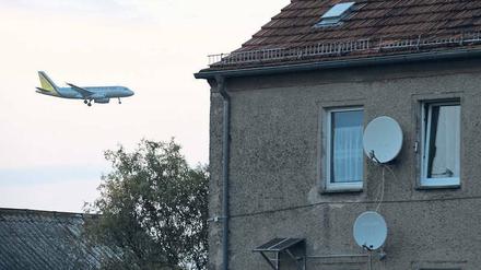 Hier rauscht ein Flugzeug geräuschvoll an einem Wohngebiet vorbei