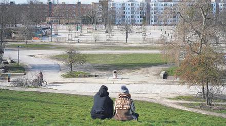 Ein junges Paar sitzt am Sonntag im leeren Mauerpark. Hier grillen, feiern, singen sonst Tausende.