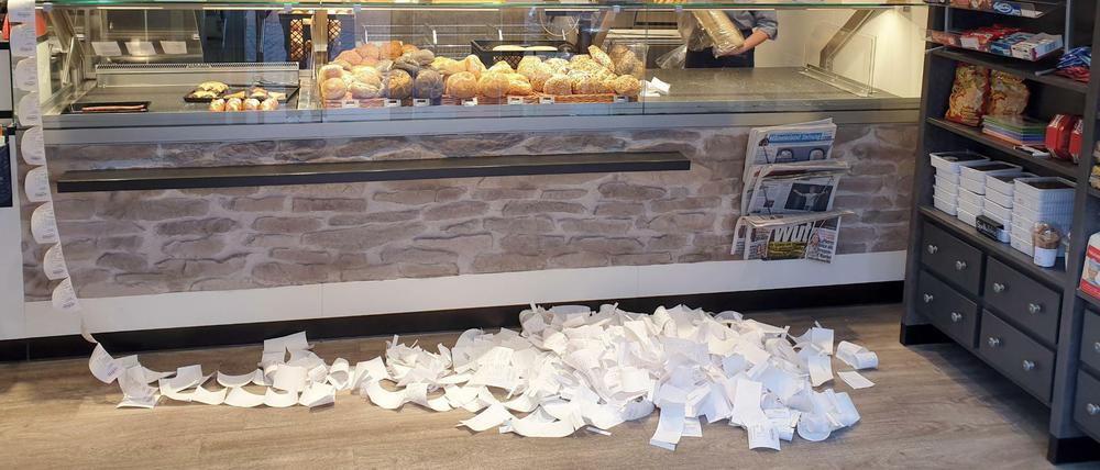 Riesiger Papierverbrauch: Die gesammelten Kassenzettel von zwei Tagen liegen in einer Bäckerei auf dem Boden.