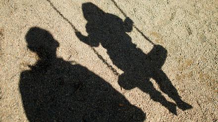 Der Schatten von einem Mann und einem schaukelnden Kind (Symbolfoto).