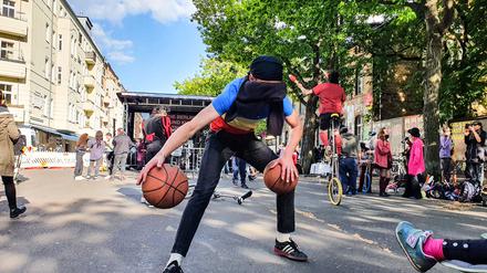 Ein Straßenkünstler dribbelt zwei Basketbälle mit verbundenen Augen vor der Bühne in der Revaler Straße.