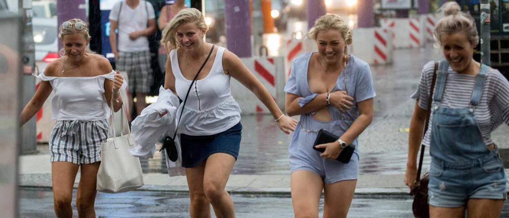 Touristinnen laufen in Berlin am Checkpoint Charlie durch den Regen. 