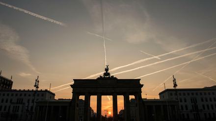 Im Licht der aufgehenden Sonne ist das Brandenburger Tor nur als Silhouette zu erkennen.