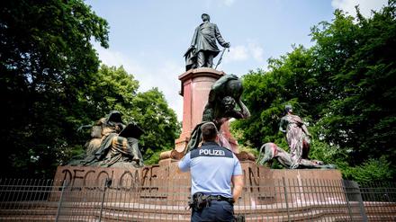 Ein Polizist steht vor dem mit Farbe beschmierten Bismarck-Nationaldenkmal in Berlin, wobei ebenfalls der Schriftzug "Decolonize Berlin" aufgesprüht wurde. 