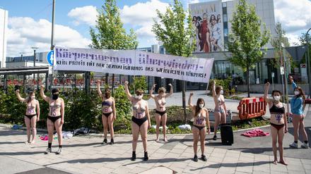 Mit Körperfarbe bemalte Aktivistinnen vom Augsburger Klimacamp demonstrieren vor einem Gebäude von ProSieben.