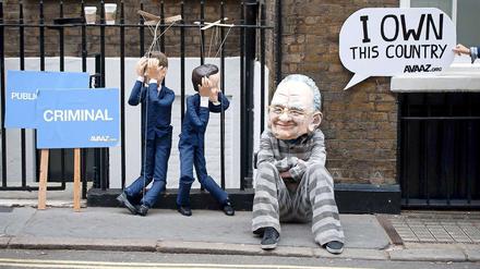 Der britische Premier Cameron und Kulturminister Jeremy Hunt als Marionetten, Medienmogul Rupert Murdoch in Gefangenenkleidung: Protestaktion in London.