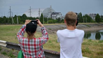Besucher der Sperrzone fotografieren den von einem Sarkophag ummantelten Reaktor von Tschernobyl. 