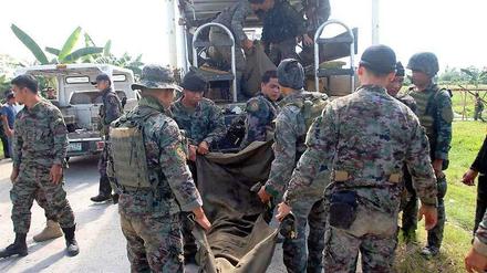 Polizisten einer philippinischen Eliteeinheit tragen einen von Rebellen getöteten Kameraden in den Mannschaftswagen. 