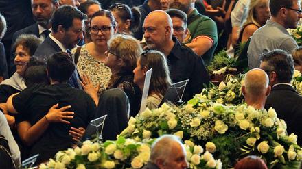 Matteo Salvini (Mitte,links), Innenminister von Italien, spricht bei seiner Ankunft an der Trauerfeier für die Opfer der Brücken-Katastrophe im Ausstellungszentrum Fiera di in Genua mit Trauernden.