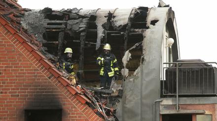 Feuerwehrleute suchen in dem beschädigten Wohnhaus nach Spuren.
