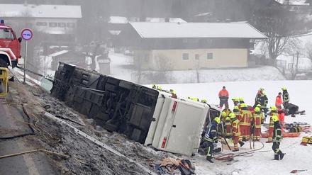 Rettungskräfte stehen auf der Bundesstraße B306 am Ortsausgang von Inzell neben einem umgekippten Reisebus.