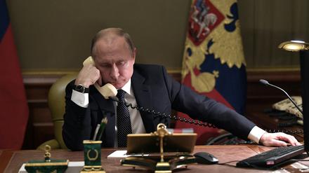 Russian President Vladimir Putin speaks on the phone in his office in Saint Petersburg on December 15, 2018 with Artyom Palyanov -- a boy with brittle bone disease who wished to see a bird's eye view of the city. - Earlier the President promised to make his dream come true by sending him on a helicopter tour of the city. (Photo by Alexey NIKOLSKY / Sputnik / AFP)