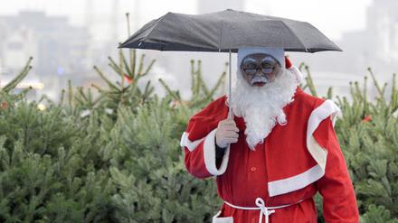 Ein Weihnachtsmann schützt sich am 10.12.2009 im Hamburger Hafen an Deck des Hafenrundfahrtsschiffes „Hamburg“ mit einem Schirm gegen den Dauerregen.