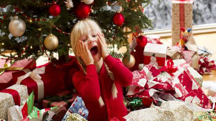 a girl screaming while opening Christmas giftssitting in a pile of wrapping paper