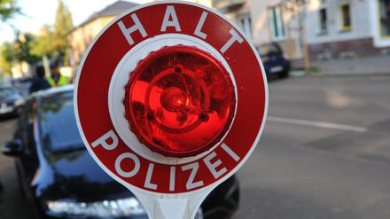 Ein Polizist stoppt in Berlin mit einer Kelle ein Auto. (Symbolbild)