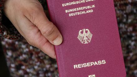 Eine Frau mit Migrationswurzeln hält ihren deutschen Reisepass in den Händen. 