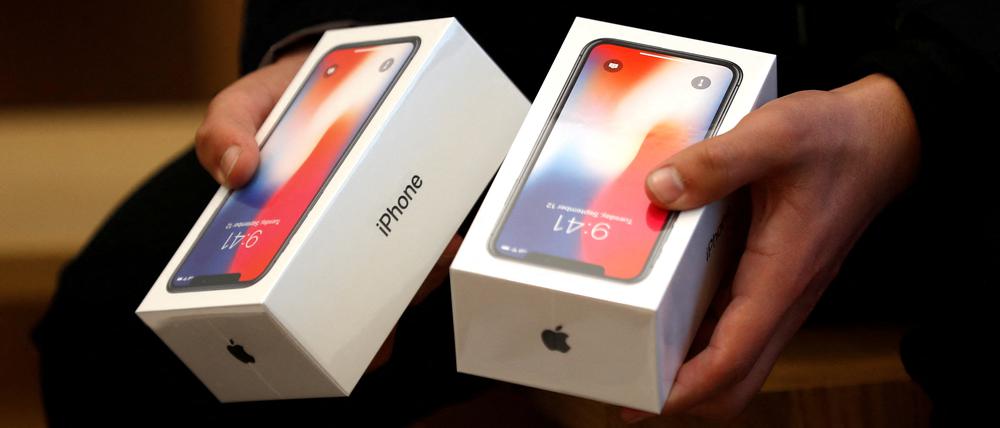 Ein Mann hält zwei Boxen für das iPhone X von Apple (Symbolbild).