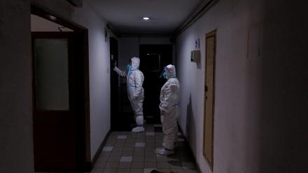 Mitarbeiter der Gesundheitsbehörden kontrollieren in Peking Apartments, die im Lockdown sind.  