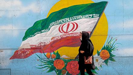 Eine Frau läuft an einer Mauer in Teheran vorbei. 