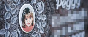 Ein Gedenkstein mit dem Porträt des Mädchens Peggy auf einem Friedhof.