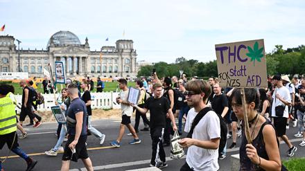 A Participant walks with a sign reading "THC instead of AfD" in front of the Reichstag building during the annual Hemp Parade (Hanfparade), a demonstration for the legalization of hemp, in Berlin's on August 12, 2023. (Photo by Tobias SCHWARZ / AFP)