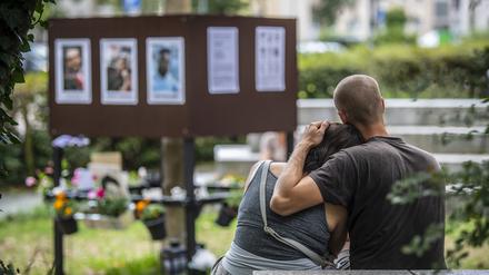 Eine Frau lehnt sich am Tatort in Hanau-Kesselstadt an die Schulter eines Mannes.