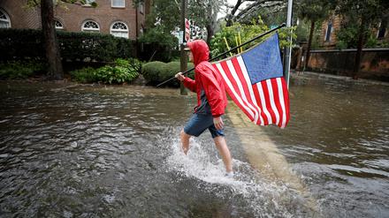 Caden Simmons, ein 16-jähriger Anwohner, geht am 30. September 2022 mit einer US-Flagge auf einer überfluteten Straße spazieren.