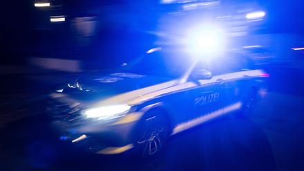 Ein Polizeifahrzeug fährt mit Blaulicht an einem Gebäude vorbei.