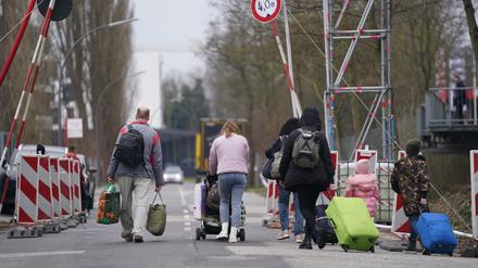 Ukrainische Flüchtlinge verlassen mit ihrem Gepäck eine Flüchtlingsunterkunft. 