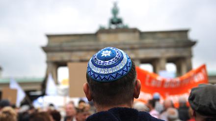Ein Teilnehmer mit Kippa der Kundgebung «Steh auf! Nie wieder Judenhass!» des Zentralrats der Juden in Deutschland steht vor dem Brandenburger Tor in Berlin. 