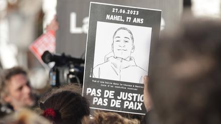 Ein Pappschild mit einem Bild von Nahel bei einer Demonstration in Frankreich
