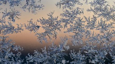14.12.2022, Brandenburg, Sieversdorf: Eisblumen sind zum Sonnenaufgang bei minus neun Grad Celsius an einer Scheibe eines Autos zu sehen. 
