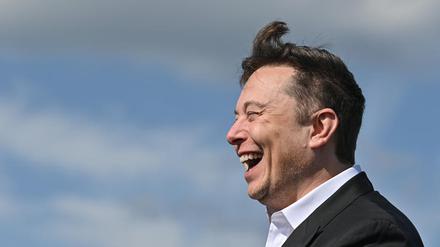 Elon Musk, Tesla-Chef, steht lachend auf der Baustelle der Tesla Gigafactory. 