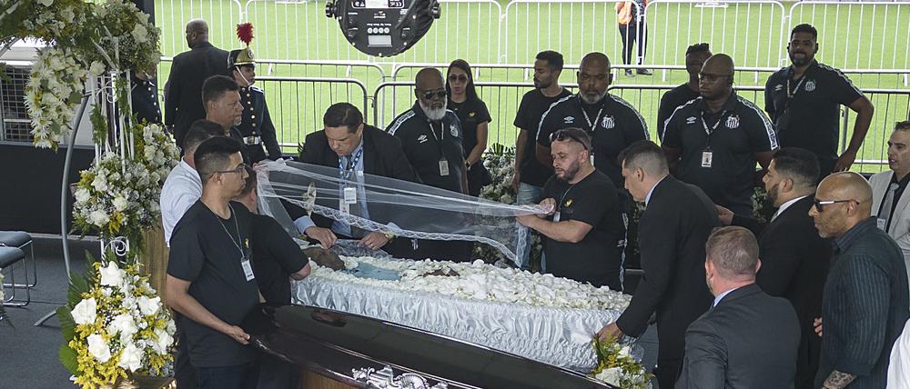 Beerdigungshelfer decken den Sarg des verstorbenen brasilianischen Fußballstars Pele auf. 