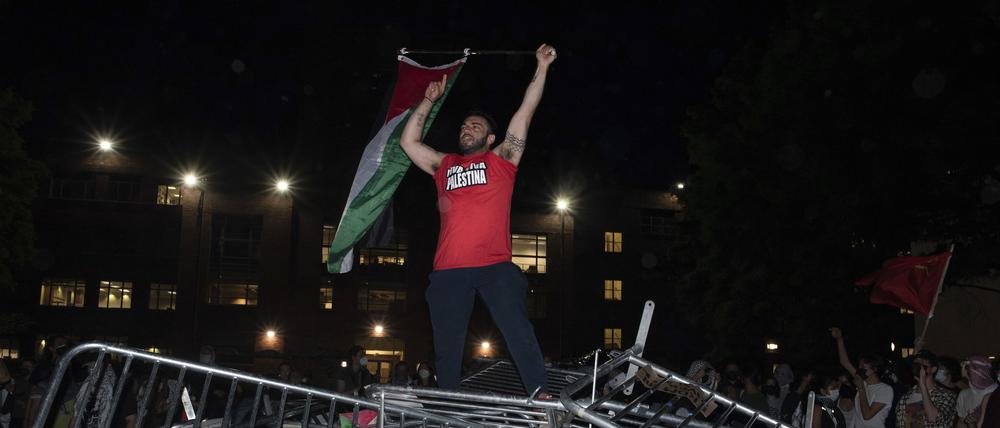 Ein Student der George Washington University schwenkt eine palästinensische Flagge, während er auf einer Polizeisperre steht.