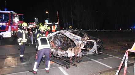Rettungskräfte stehen am Wrack eines zerstörten Autos nach einem Unfall an einem Bahnübergang. Ein Mensch ist beim Zusammenstoß eines Autos mit einem Zug an einem Bahnübergang in Bestensee (Landkreis Dahme-Spreewald) ums Leben gekommen. 