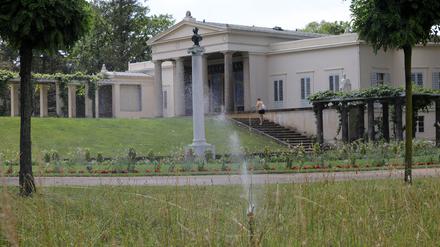 Warum werden Grünflächen (Park Sanssouci) in Potsdam tagsüber gewässert? In der Nachmittagshitze laufen die Wassersprinkler am Schloß Charlottenhof.
