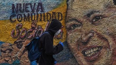 Relikte eines sozialistischen Scheiterns. Ein Mann mit Maske passiert im coronageplagten Caracas am 28. Juli 2020 ein Wandgemälde des verstorbenen Staatspräsidenten Hugo Chávez.