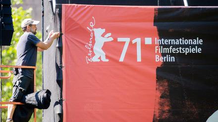 Ein Arbeiter befestigt ein Berlinale-Banner.