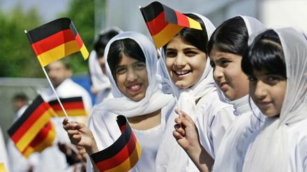 Muslimische Mädchen schwenken deutsche Fahnen.