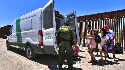 Ein US-Grenzschützer und lateinamerikanische Migranten an der mexikanischen Grenze mit Arizona.
