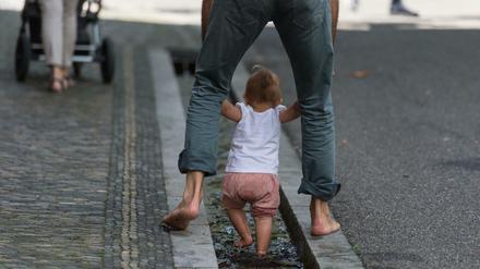 Ein Vater erfrischt sich mit seiner kleinen Tochter in Freiburg im Wasser.