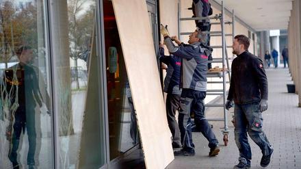 Arbeiter sichern am Freitag die Fensterscheiben an einem Hotel am Zentralen Omnibusbahnhof (ZOB) in Hannover mit Holzplatten.