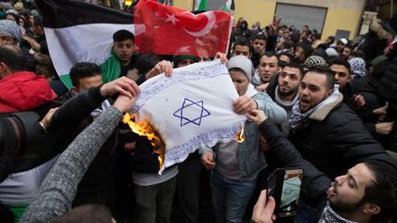 Teilnehmer einer Demonstration verbrennen in Berlin-Neukölln eine selbstgemalte Fahne mit einem Davidstern.