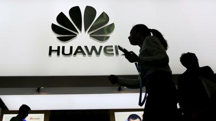 Menschen laufen an einem Huawei-Logo vorbei. (Symbolbild)